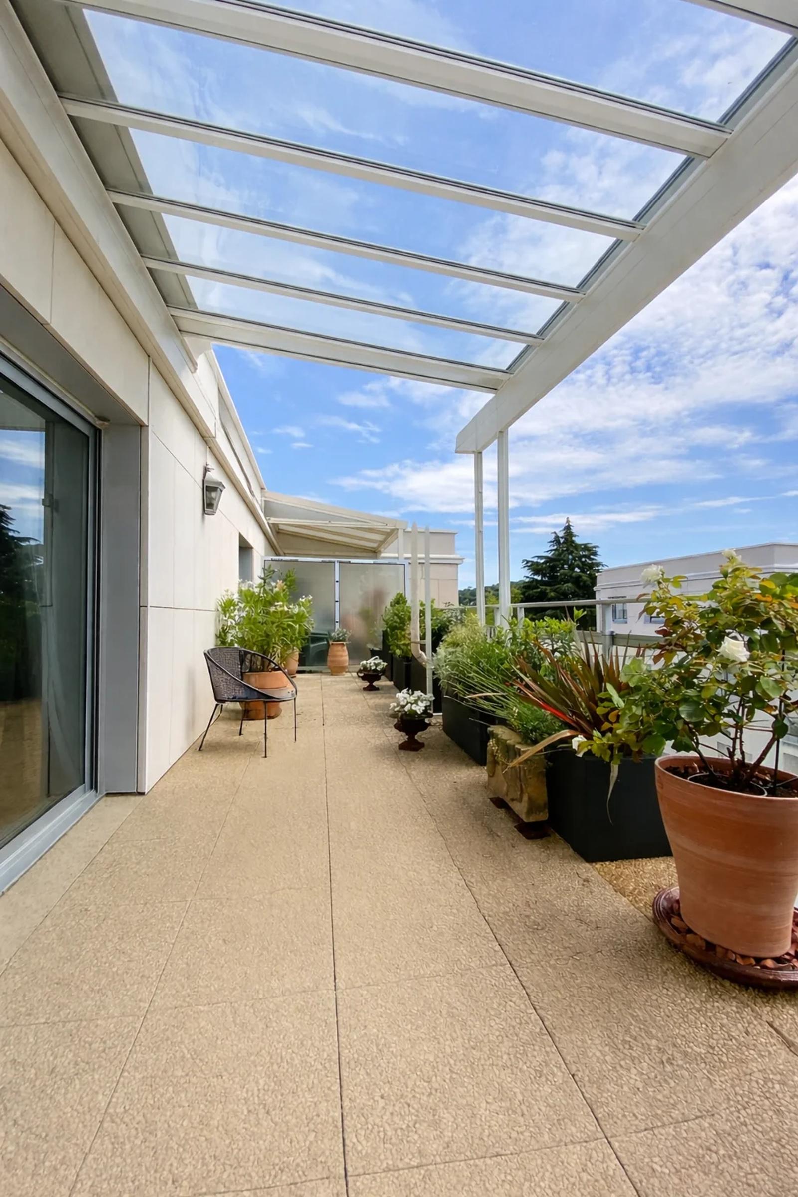 Terrasse en longueur avec pergola vitrée et plantes en pots — Croissy-sur-Seine.