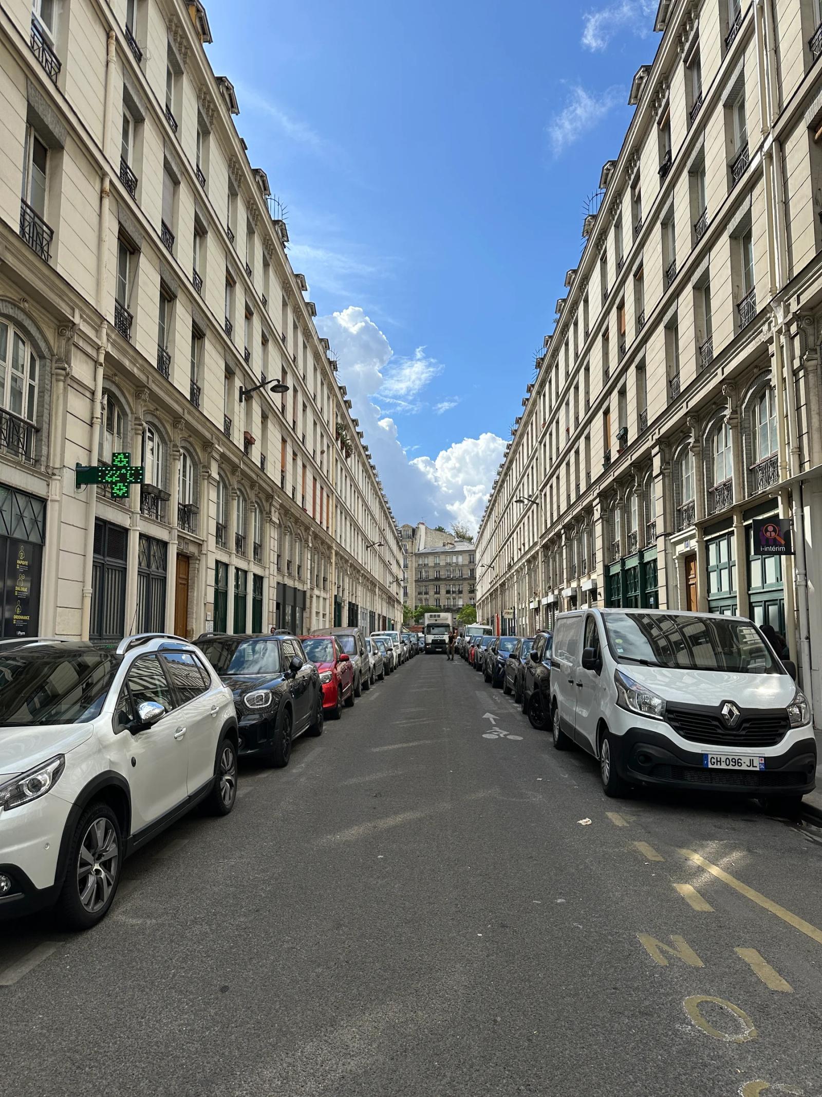 Rue bordée d’immeubles en pierre et de commerces — Paris 11e.