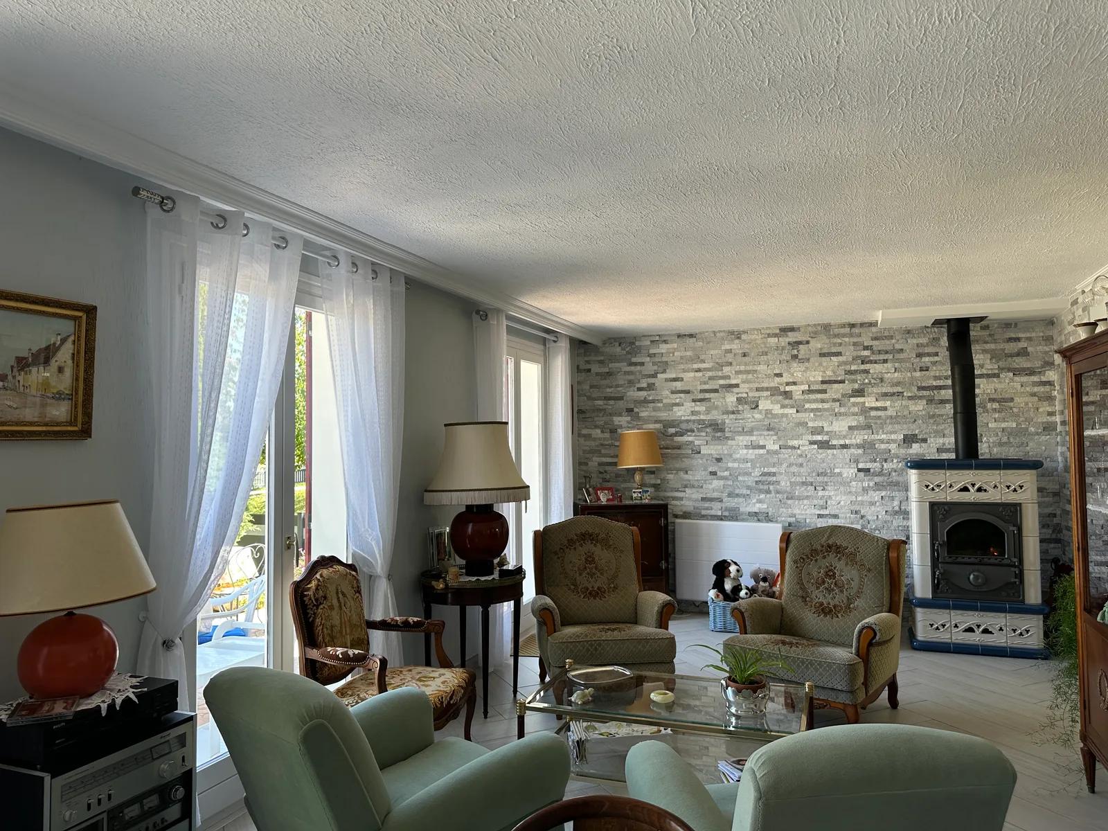 Salon avec fauteuils, baie vitrée et poêle devant un mur en parement — Maule.