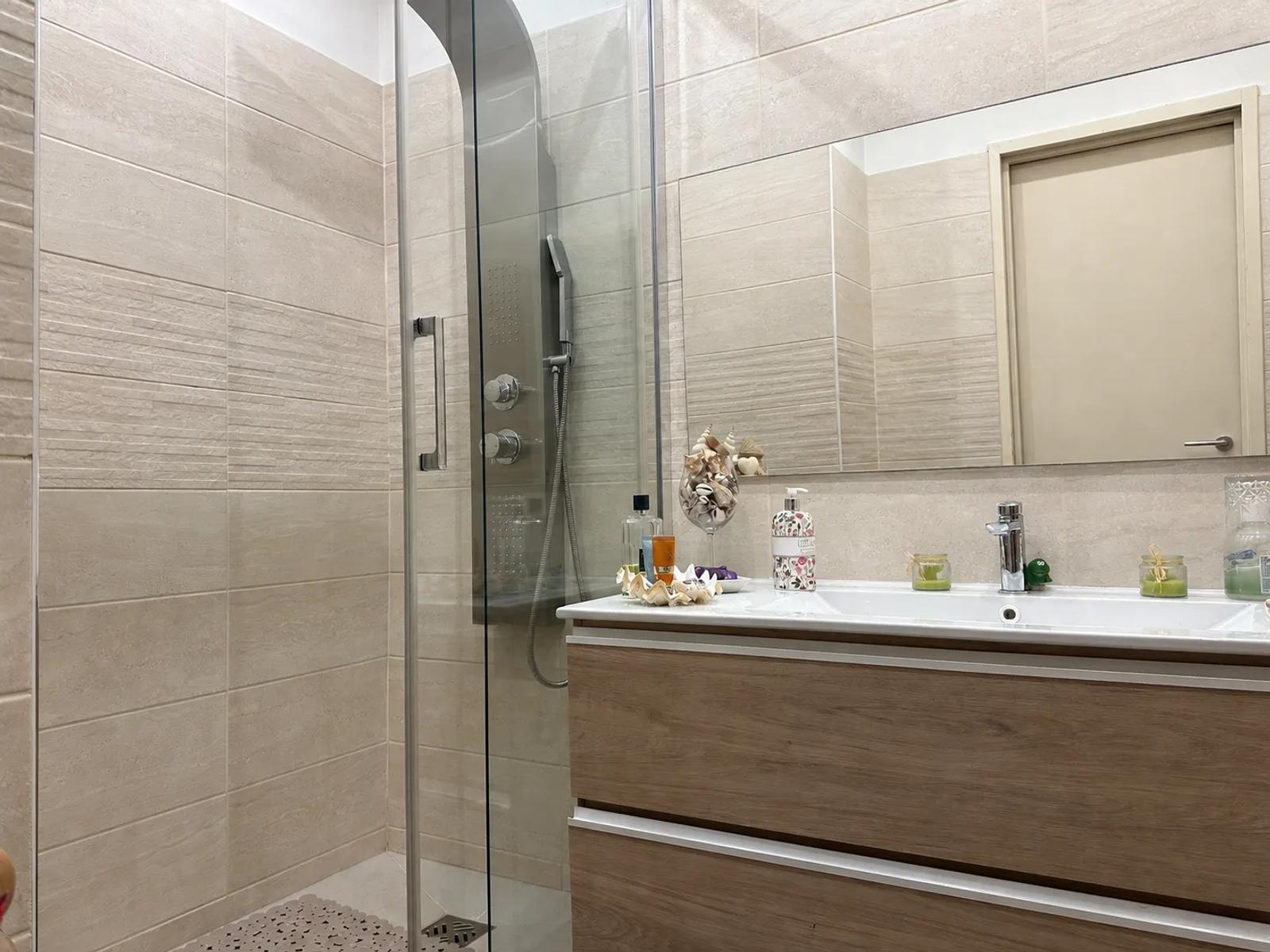 Salle d’eau avec douche vitrée et meuble vasque en bois — Versailles.