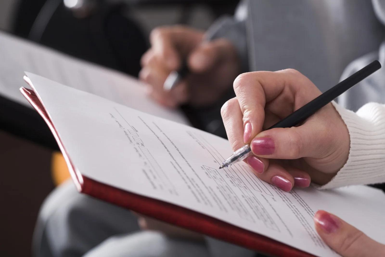 Une personne signe un document posé dans un dossier.