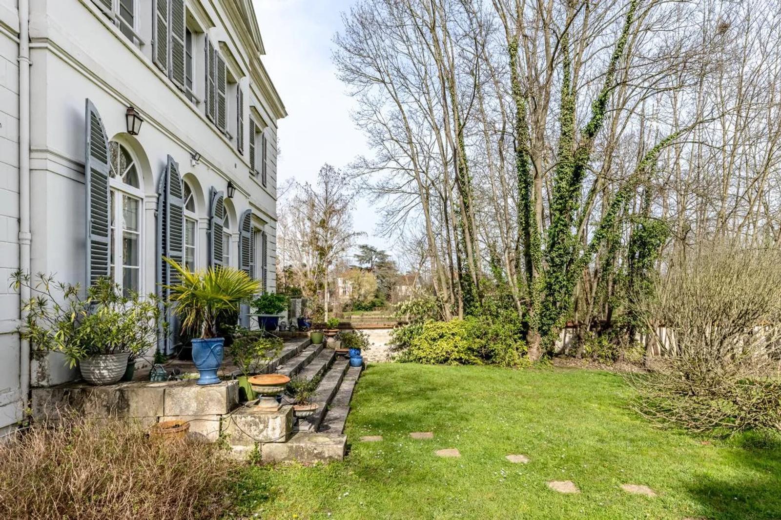 Terrasse au pied de la façade et jardin bordé d’arbres — Bougival.
