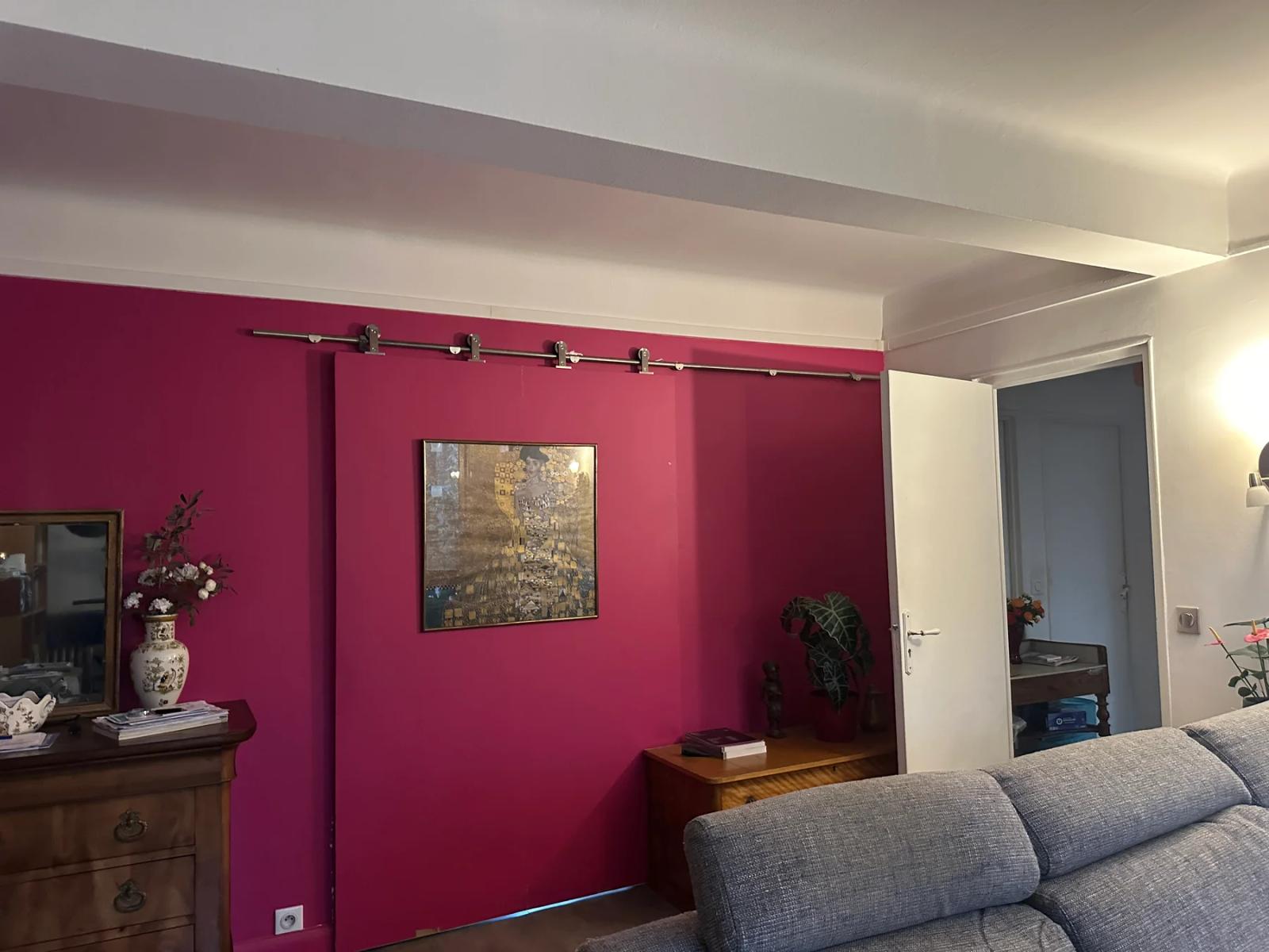 Salon avec canapé gris et porte coulissante sur un mur rose — Ville-d’Avray.