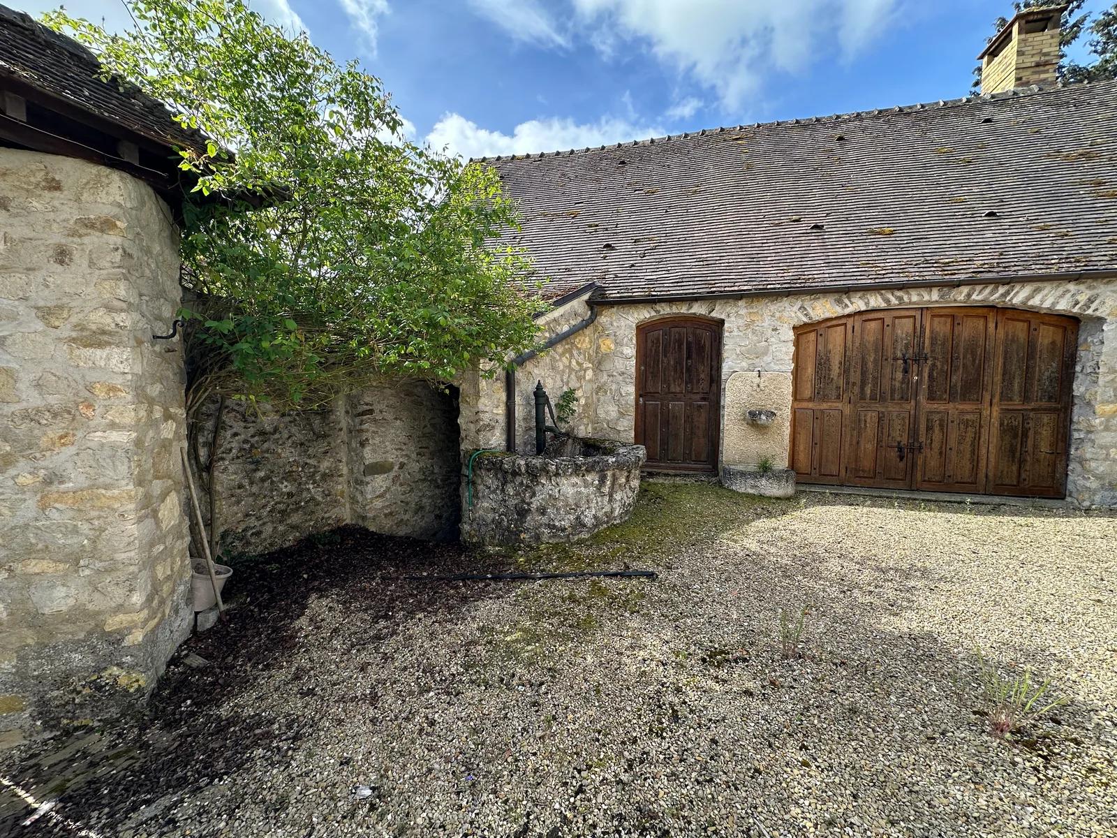 Cour gravillonnée devant une dépendance en pierre avec portes en bois — Villeconin.