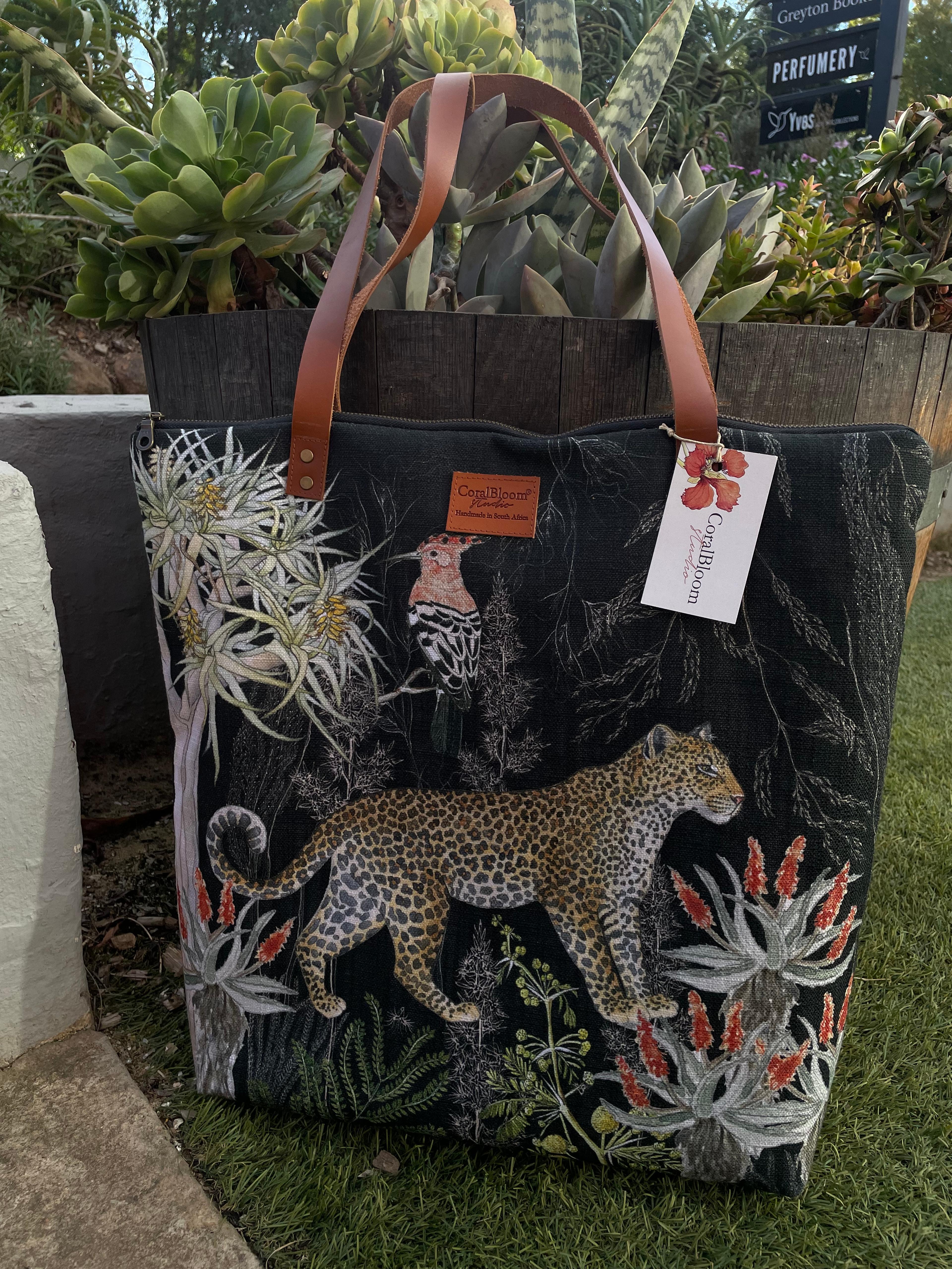 Black CoralBloom luxury tote bag printed with a watercolour leopard, white proteas and aloes
