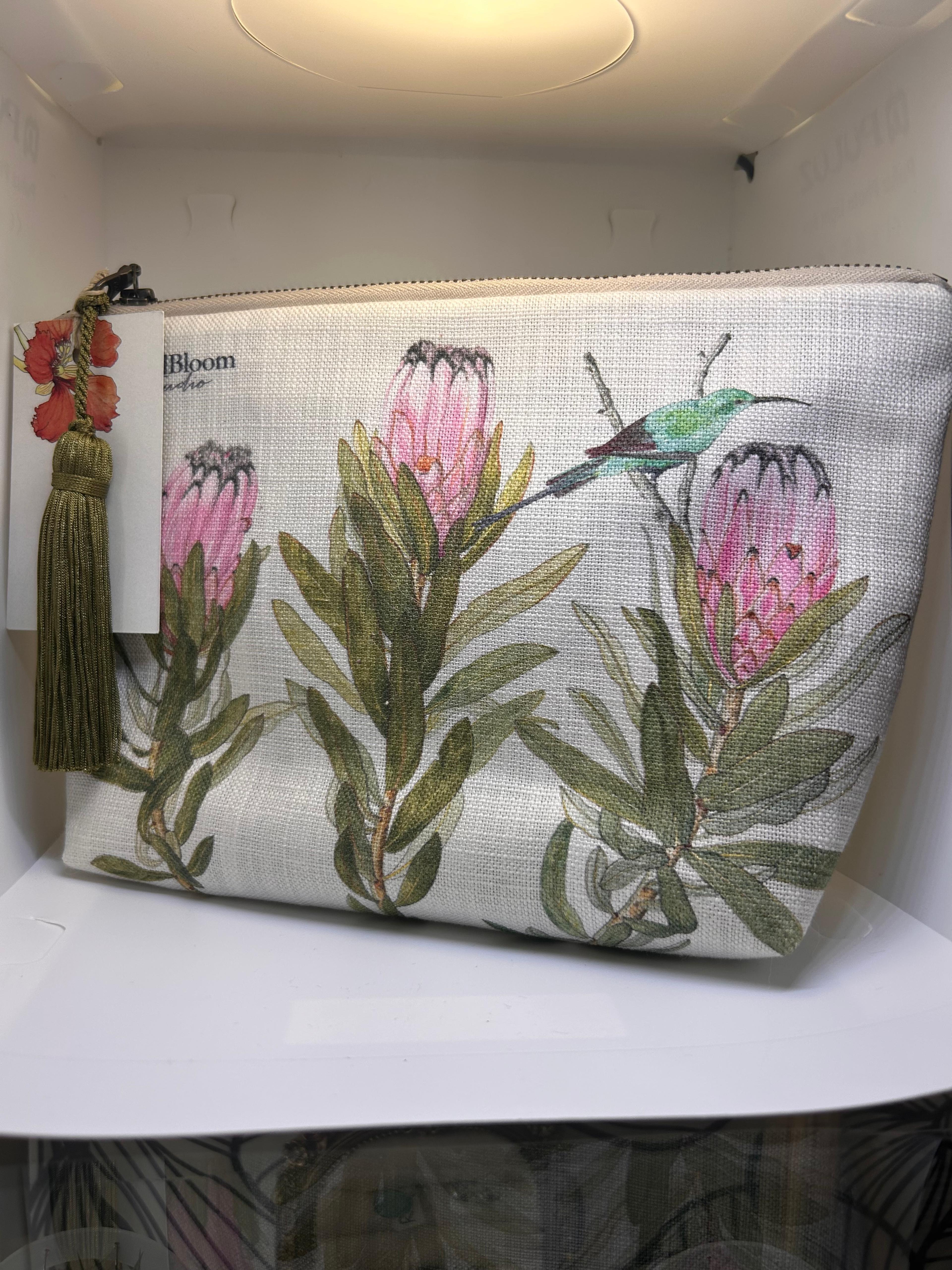 Cream CoralBloom tassel clutch bag printed with watercolour pink proteas and a sunbird, olive tassel