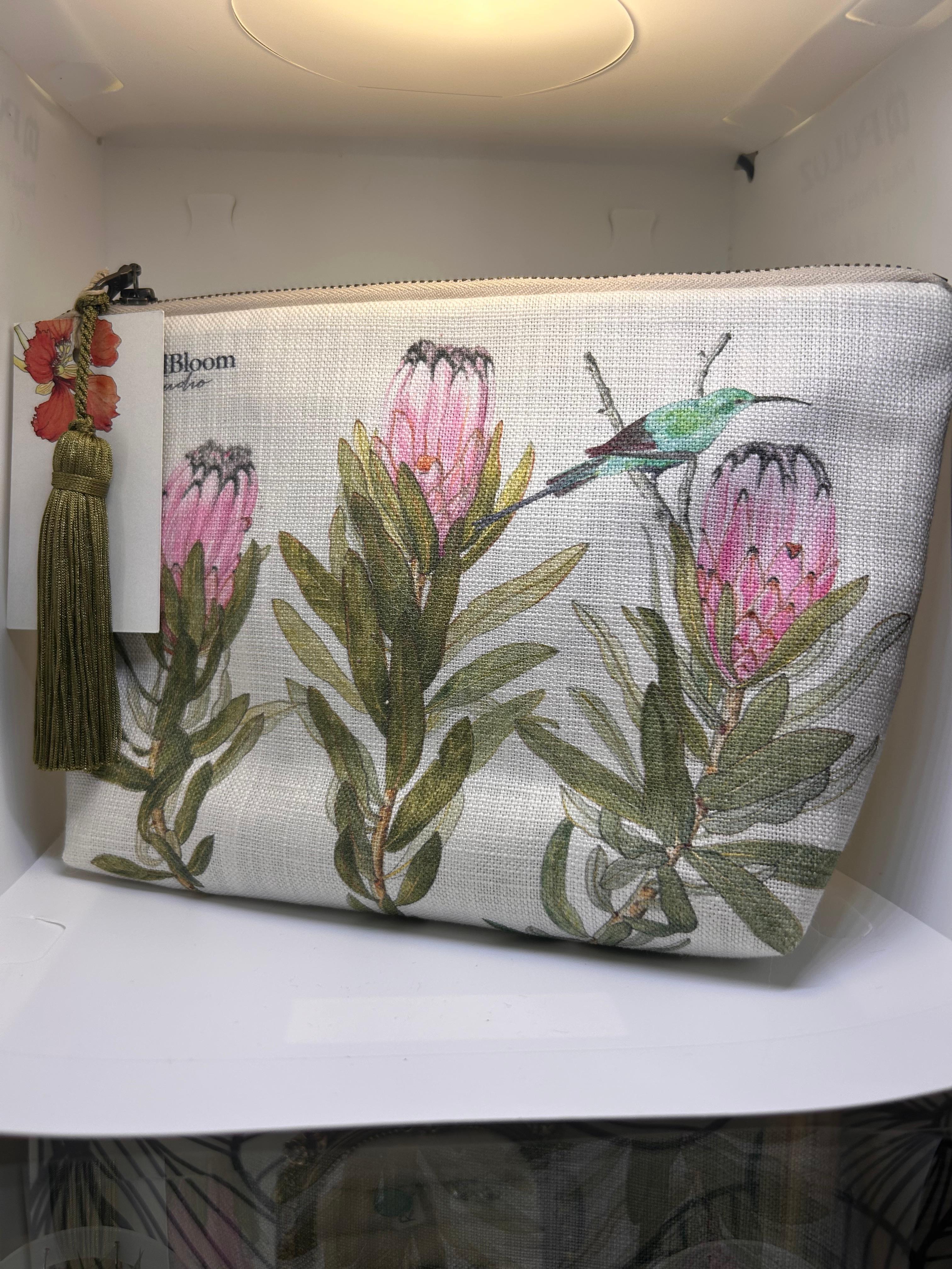 Cream CoralBloom tassel clutch bag printed with watercolour pink proteas and a sunbird, olive tassel