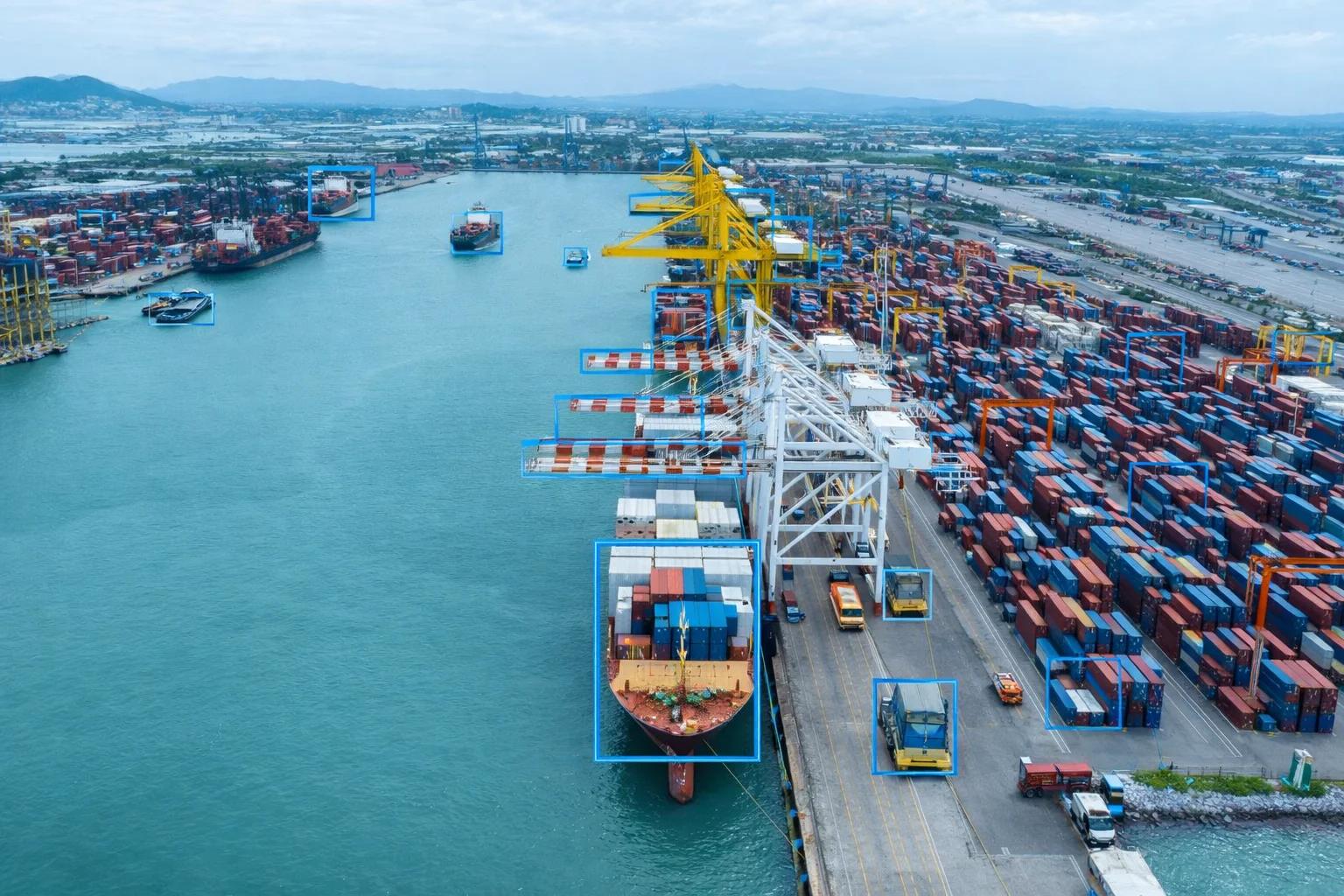 Aerial view of a cargo shipping terminal using smart port video analytics to monitor container logistics and vessel docking.