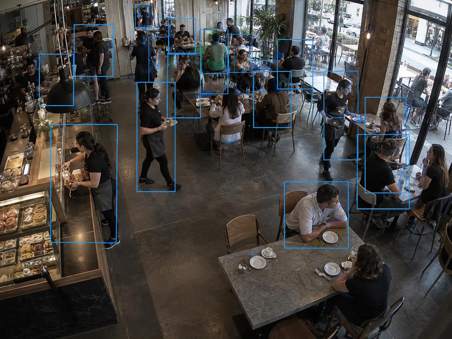 Overhead view of a busy café utilizing AI video analytics to track customer dining occupancy and waiter movement.