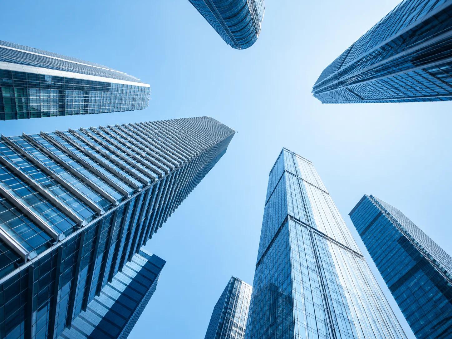Low angle view of modern glass skyscrapers illustrating smart building video analytics and security monitoring solutions.