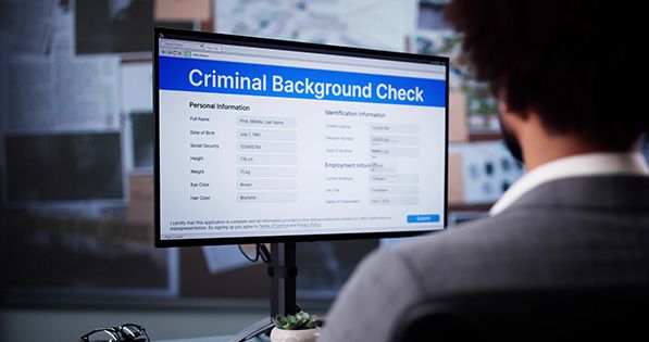 A person views a Criminal Background Check form on a desktop monitor.