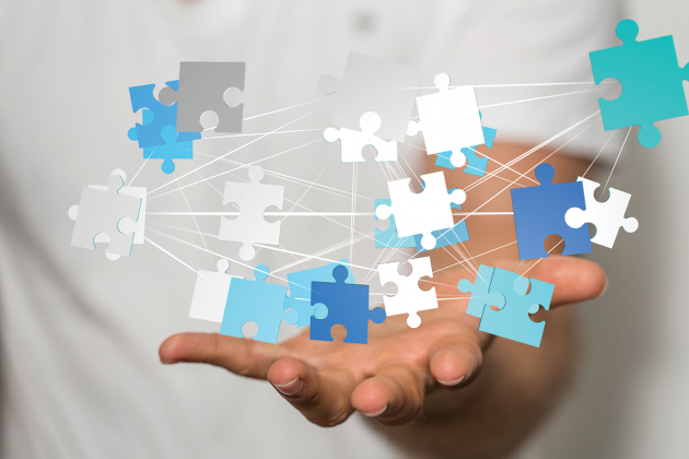 An open hand beneath floating interconnected white and blue puzzle pieces.
