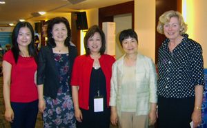 Five women pose together in an indoor event space.