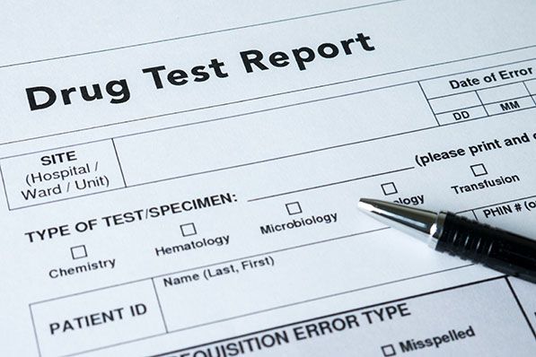 Drug Test Report form with a pen resting on it.