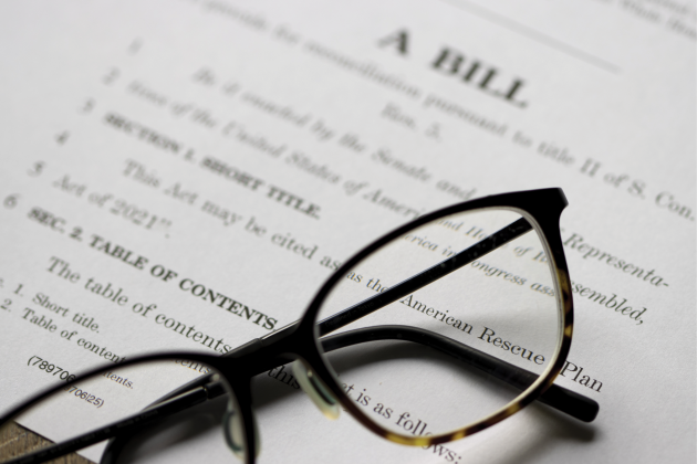 Black eyeglasses rest on a printed bill titled American Rescue Plan Act.