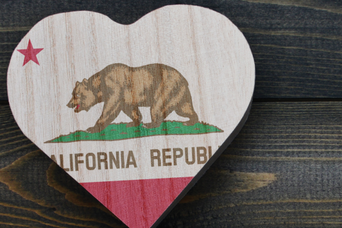 A heart-shaped wooden plaque painted with the California Republic flag rests on dark wood.