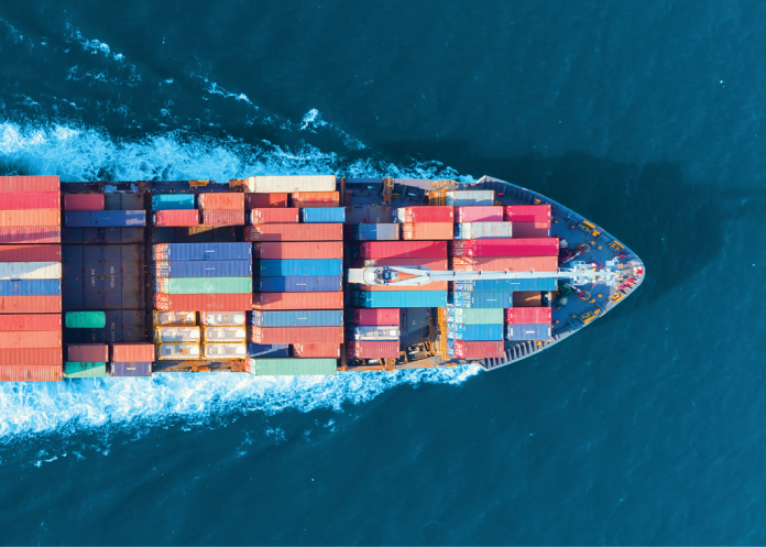 Overhead view of a cargo ship carrying colorful containers through deep blue water.