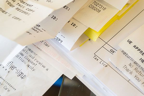 A close-up of a messy pile of various paper receipts and documents.