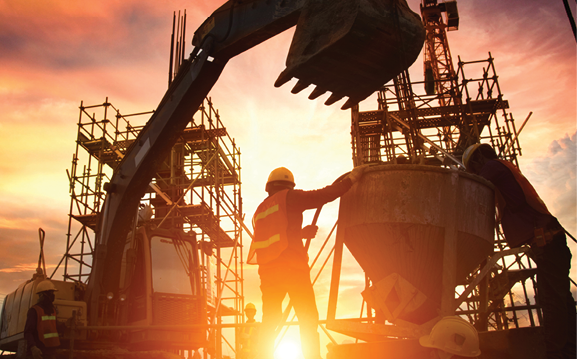 Construction workers and heavy equipment silhouetted against the setting sun.