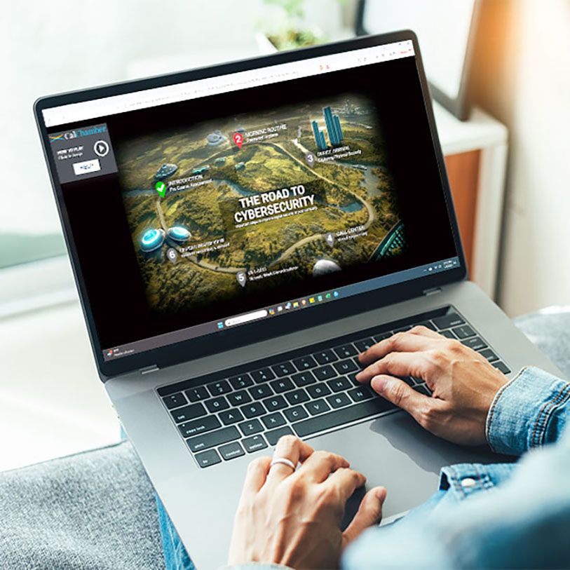 A person uses a laptop displaying The Road to Cybersecurity training map.
