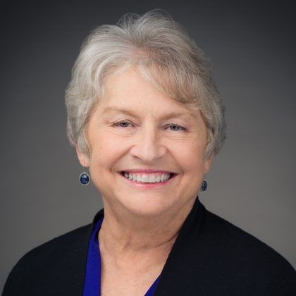 Smiling woman with short gray hair and blue earrings.