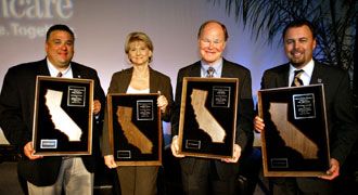 Four people hold framed awards featuring silhouettes of California.