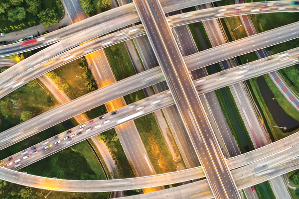 Aerial view of a multilayer highway interchange with curved ramps and moving vehicles.