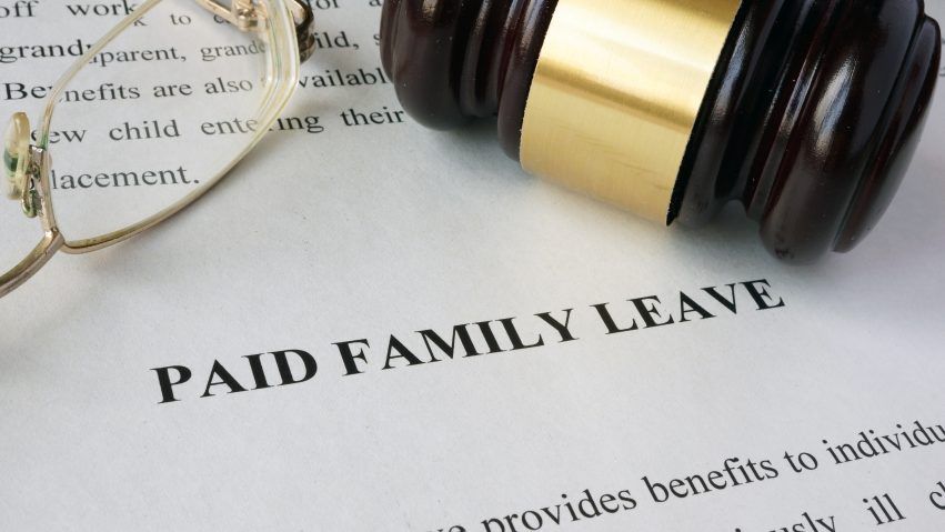 A judge’s gavel and eyeglasses rest on a document headed PAID FAMILY LEAVE.