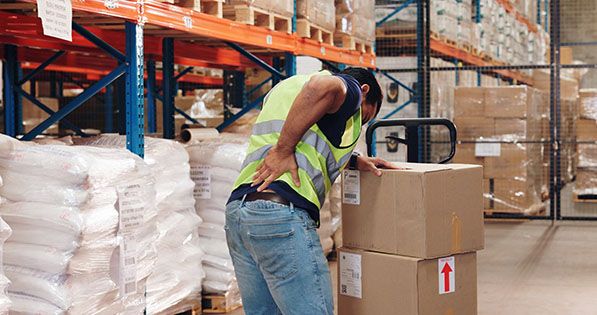 Warehouse worker holding their lower back in pain.