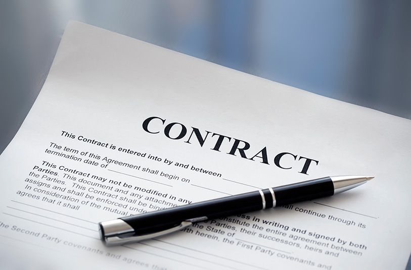 A black pen rests diagonally on a document titled CONTRACT.