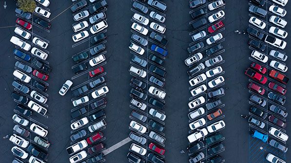 Overhead view of tightly packed diagonal rows of cars in a parking lot.