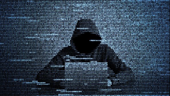 Silhouette of a hooded person at a laptop overlaid with rows of digital code.