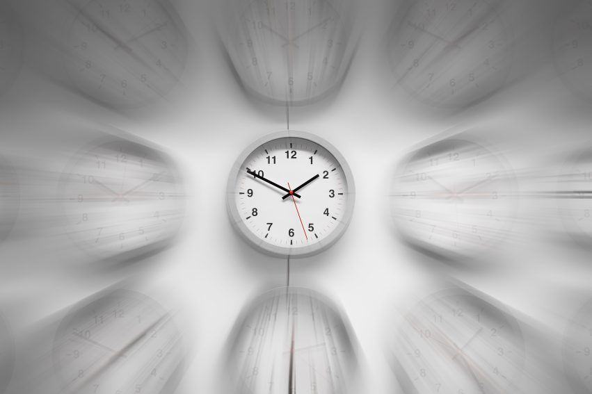 A wall clock remains sharp at the center of a gray radial motion blur.