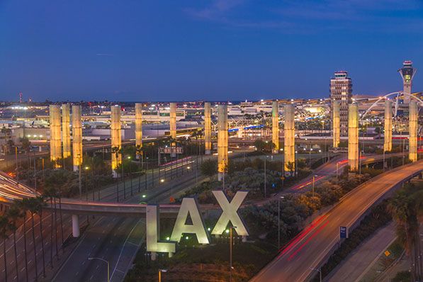 Illuminated LAX letters and glowing airport pylons at twilight.