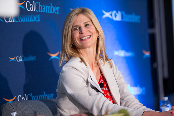 A blonde woman in a light blazer smiles while seated before a CalChamber backdrop.
