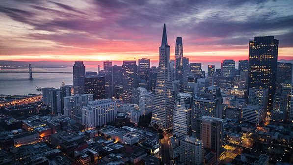 The San Francisco skyline and Bay Bridge beneath a colorful sunset.