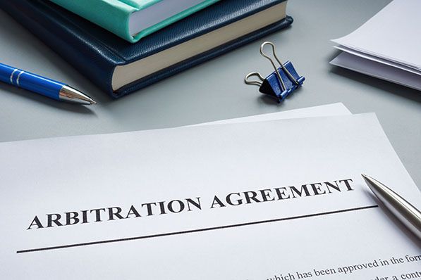 Arbitration Agreement document with a pen and office supplies.