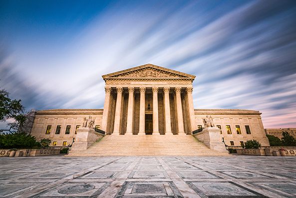 The U.S. Supreme Court building across an empty plaza beneath a streaked sky.