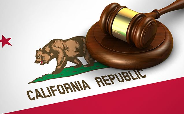 A wooden gavel and block rest on a California Republic flag.