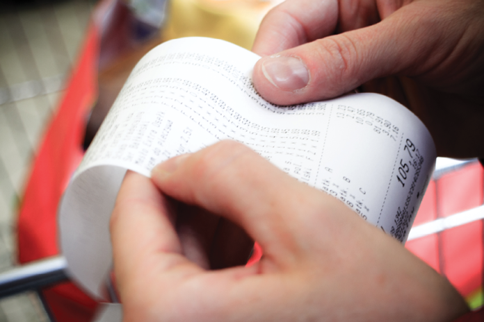Close-up of hands holding and checking a long printed receipt.