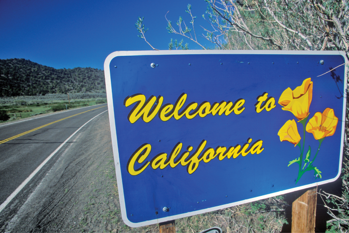 A Welcome to California roadside sign decorated with yellow poppies.