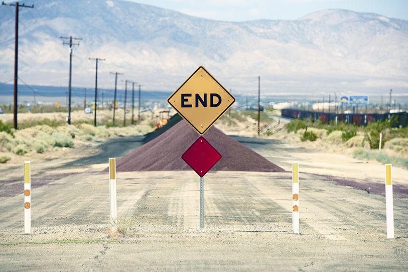 A yellow END sign marks a blocked road stretching toward distant mountains.