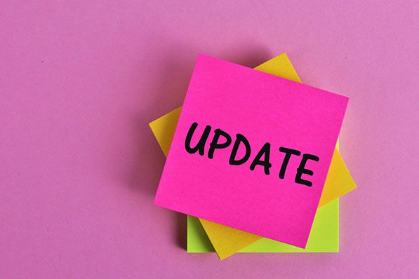 Bright pink sticky note reading UPDATE over a stack of colorful notes.