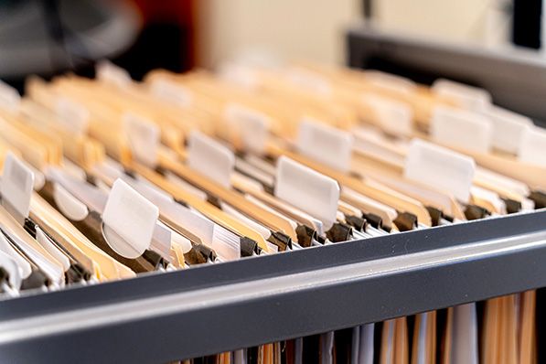 Rows of labeled hanging folders in an open filing cabinet drawer.