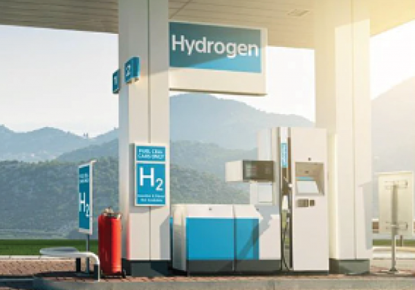 Hydrogen fueling pumps marked H2 stand beneath a Hydrogen sign, with hills in the background.