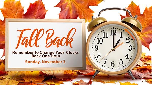Fall Back reminder beside an alarm clock and autumn leaves: change clocks back one hour on Sunday, November 3.