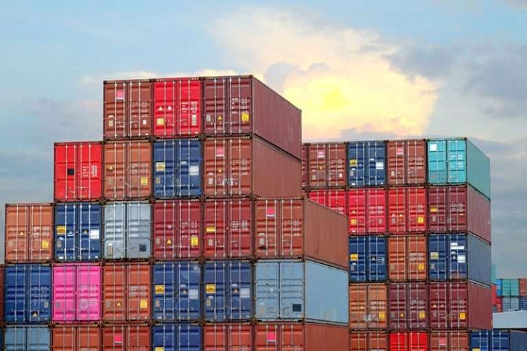 Stacks of multicolored shipping containers beneath a cloudy sky.