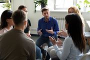 A group of six people sitting in a circle, engaged in a discussion.