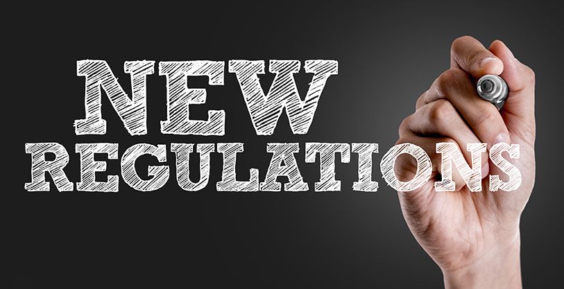A hand holds a marker beside the words New Regulations on a dark background.