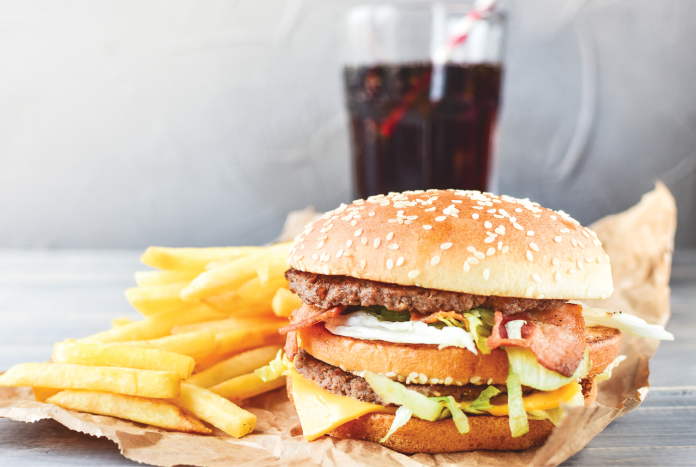 A hamburger, French fries and a glass of cola on a table.